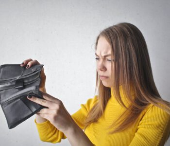 Eine Frau wirft einen frustrierten Blick in einen leeren Geldbeutel