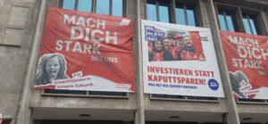 Transparente an einer Hauswand mit Aufrufen zur Mitarbeit und für Investitionten statt Sparwahn