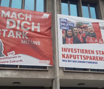Transparente an einer Hauswand mit Aufrufen zur Mitarbeit und für Investitionten statt Sparwahn